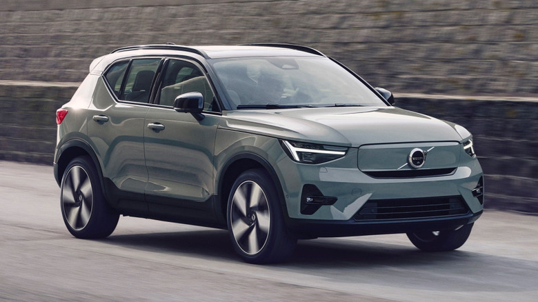 Volvo EX40 on the road by wall.