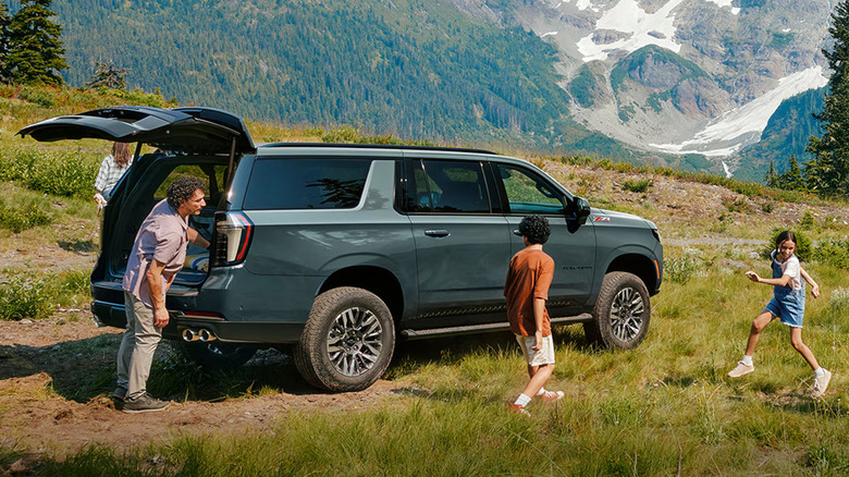 2025 Chevrolet Suburban parked in a mountainous area with a family enjoying a picnic nearby