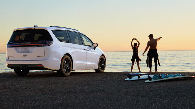 2025 Chrysler Pacifica parked near the sea with two surfers walking nearby