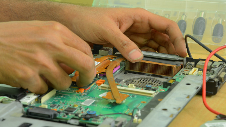 A person repairing a computer motherboard