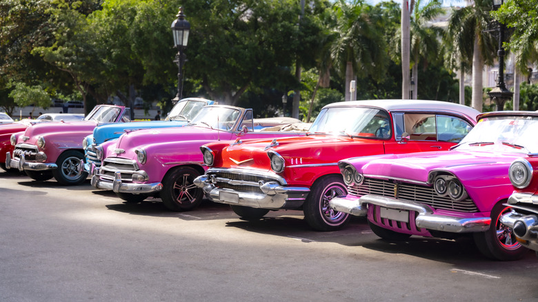 Colorful red and pink classic cars parked in a row