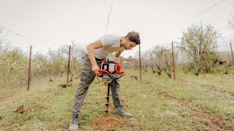 man using an earth auger tool