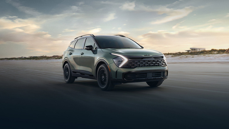 A green Kia Sportage driving on a wide roadway