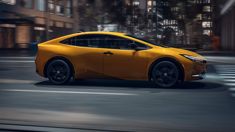 A yellow Prius driving in a city.