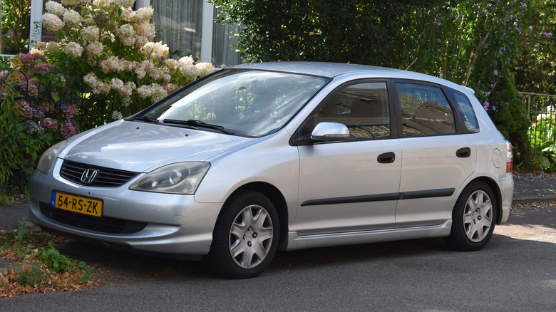 A mid-2000s Honda Civic parked in front of a house