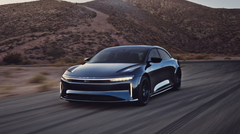 Lucid Air Sapphire sedan seen from left front on desert road at twilight