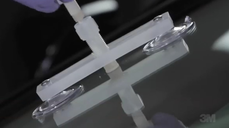 a windshield repair tool attached to glass