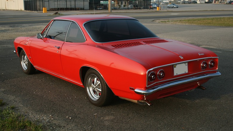 Customized red 1968 Chevrolet Corvair Monza seen from left rear in parking lot