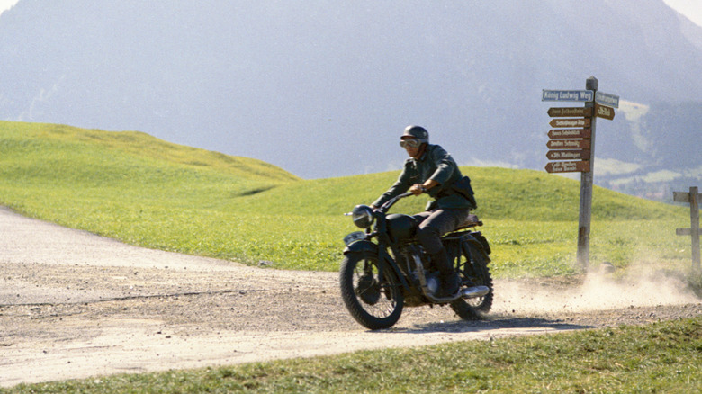 Steve McQueen riding a black Triumph TR6 Trophy on a dirt road
