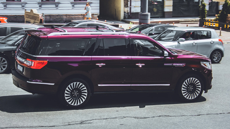 A red or burgundy Lincoln Navigator moving through a street in Ukraine.