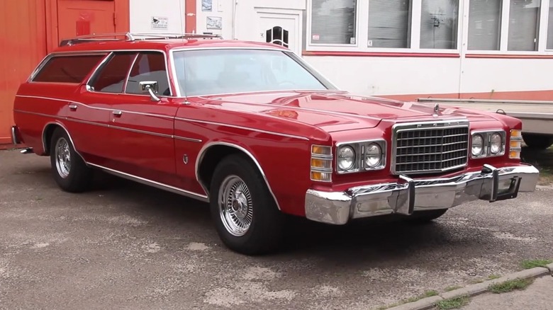 A red Ford LTD in the station wagon body style from the mid-1970s in a residential neighborhood.