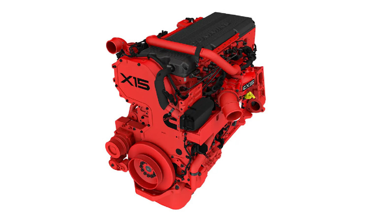 A Cummins X15 diesel engine in bright red, shown from a high-angle perspective, featuring intake and exhaust piping, belt-driven components, and labeled with 'X15' on the side.