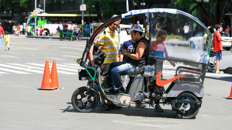 A bicycle taxi in Mexico city carrying a passenger, which for some reason has a Nike logo on the side/