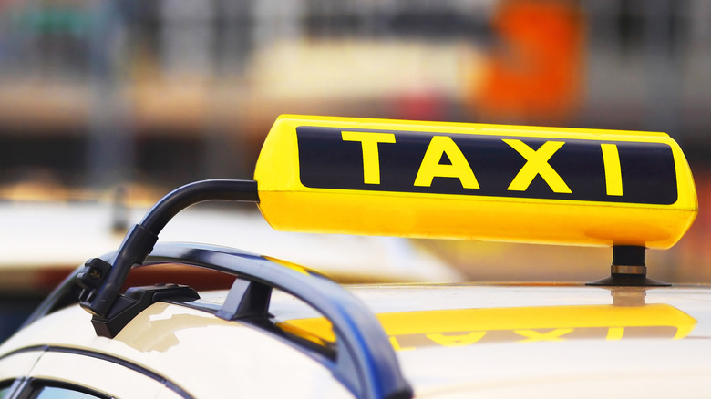 A sign on top of a yellow city cab that says 