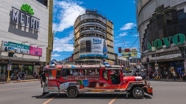 A brightly colored Jeepney trundling about a busy road in Manila, Philippines