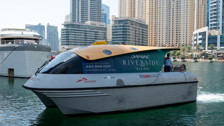 A silver RTA Dubai Water Taxi, with the iconic Marina skyline in the background