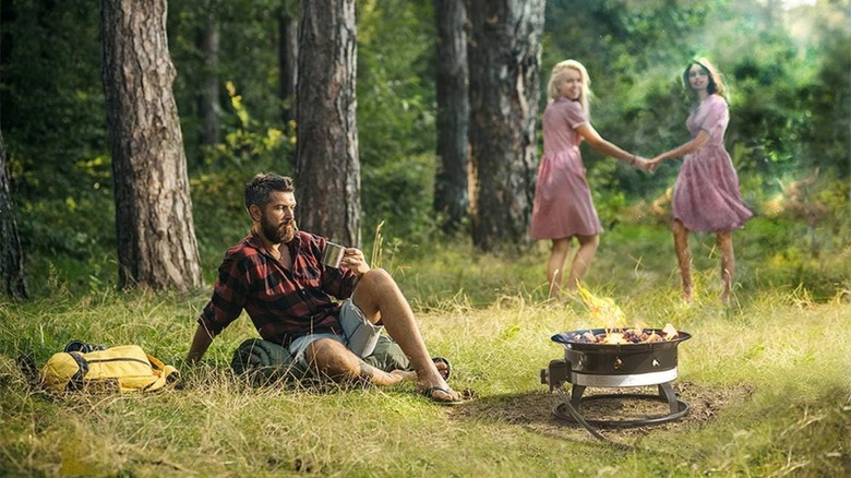 People camping in the woods with a portable fire place