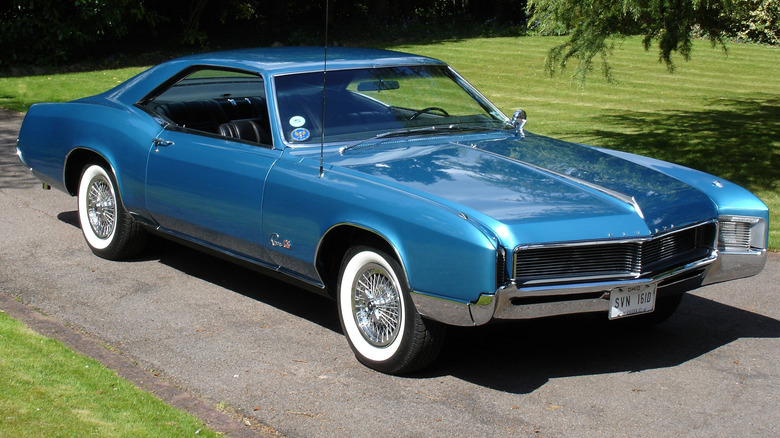 Blue 1966 Buick Riviera with headlights hidden seen from right front parked outdoors
