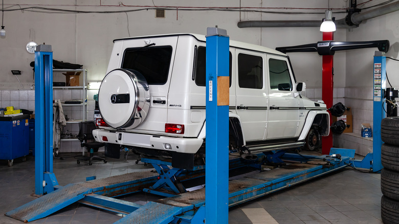 A white G-Wagon sitting on a blue alignment rack with all four wheels off