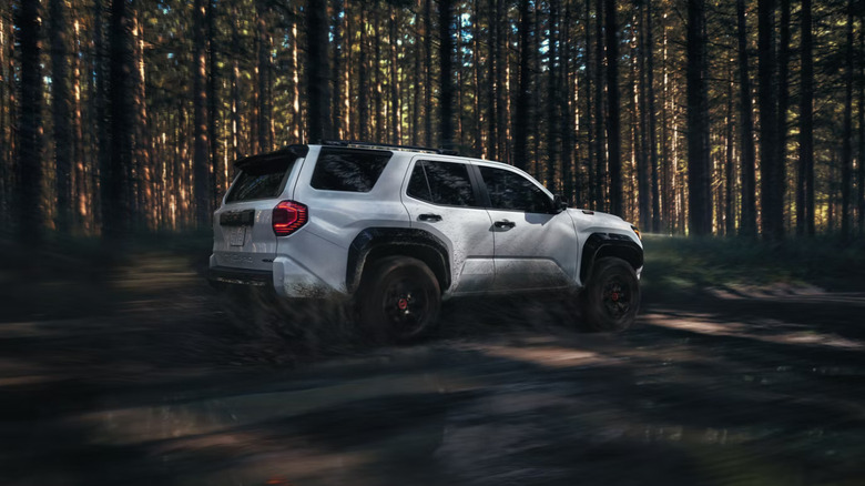 A white 2025 Toyota 4Runner TRD Pro zooming through a forest in the daytime, right side view