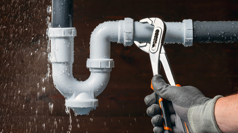 turning a sink pipe with a wrench while water spills out