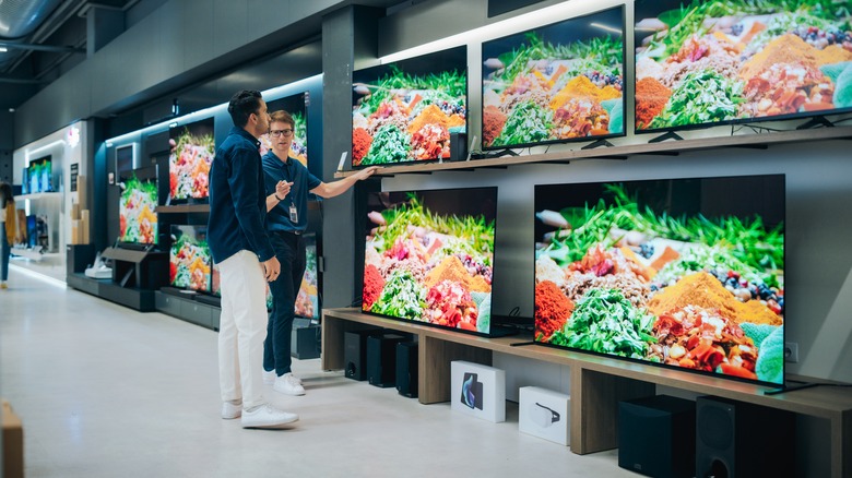 man viewing tvs with salesman