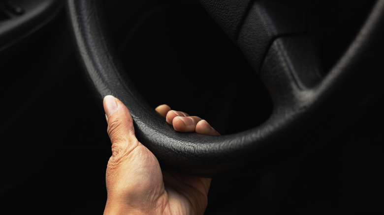a hand on the bottom of a steering wheel