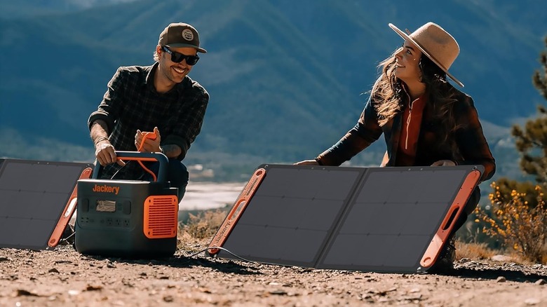 Two people with a Jackery power bank and solar panels