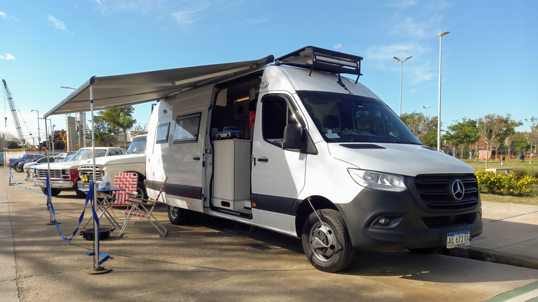 A white Mercedes-Benz sprinter that's been turned into a motorhome parked in a lot
