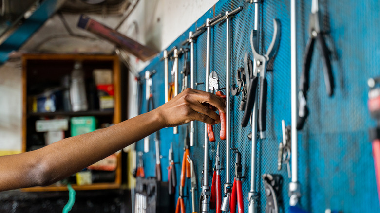 hand reaching for tool on a tool wall
