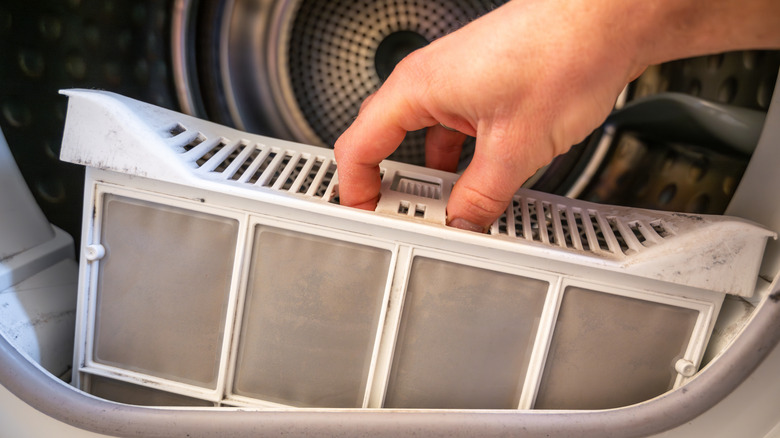 Hand removing lint trap from dryer