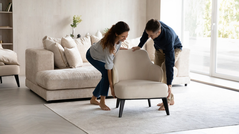 Couple moving white chair onto a white rug