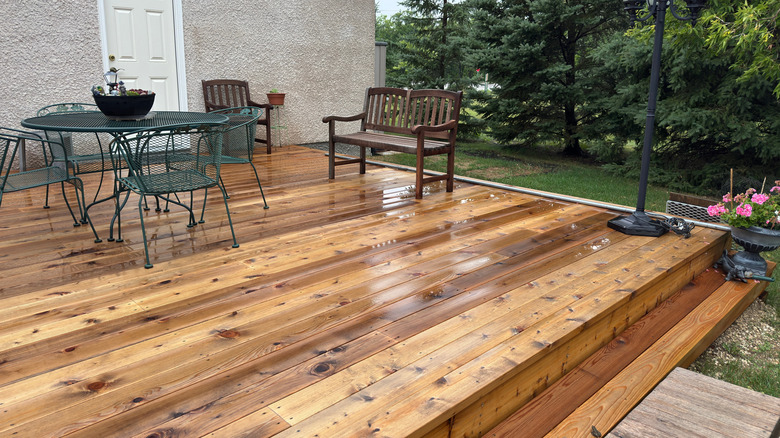 Wooden deck containing a table, chairs, and benches
