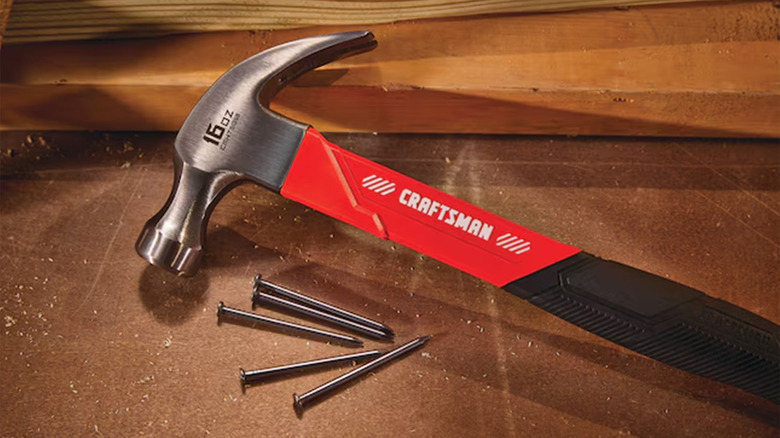 A Craftsman brand claw hammer on wood with some nails scattered about.