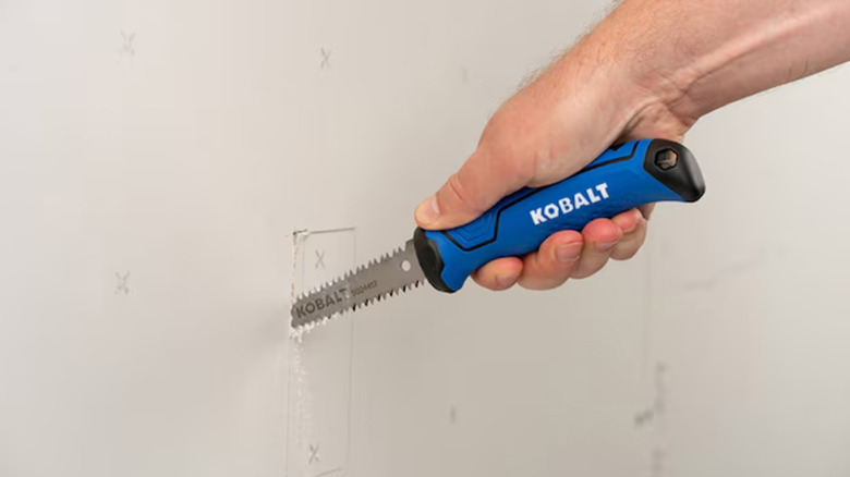 A man cutting a hole into drywall with a 6-inch jab saw
