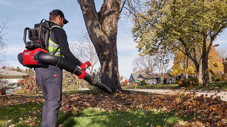 A man leaf blowing a suburban yard in the autumn