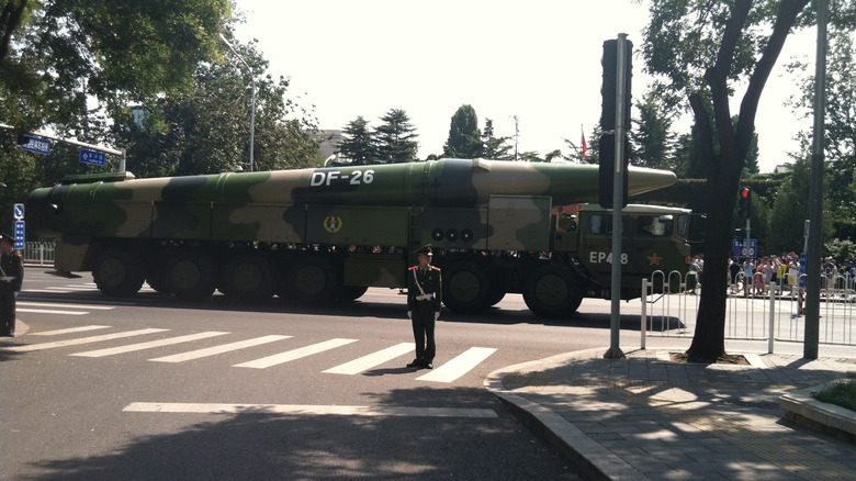 A DF-26 missile being moved through an intersection by a military truck.
