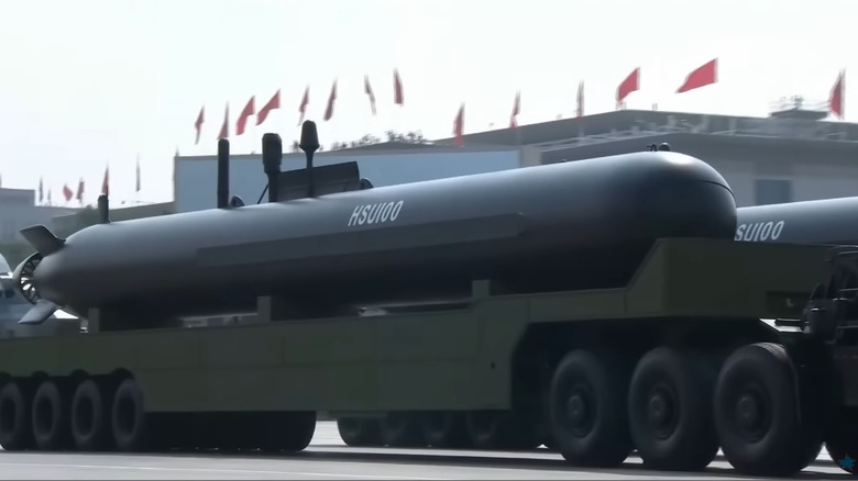 A black unmanned submarine, the HSU100 being transported alongside its twin.