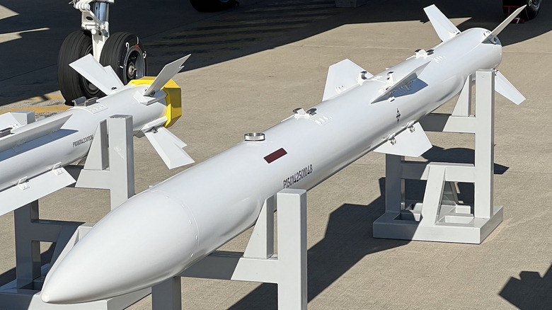 Two white Chinese PL-15 missiles on a rack on the ground.