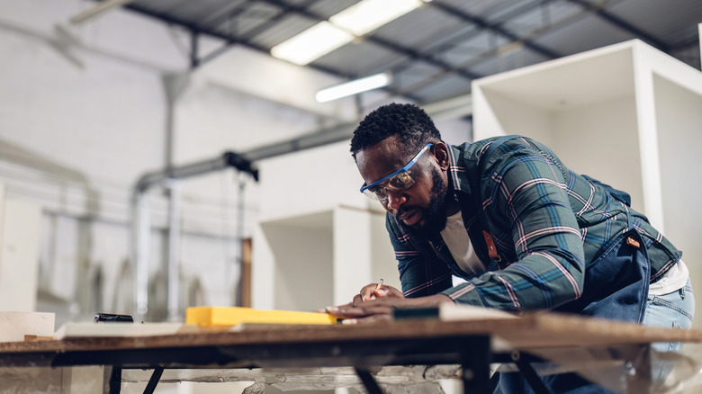 woodworker marking up a board in his shop