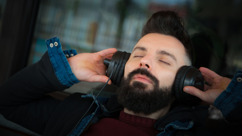 A man listening to his wired headphones while relaxing.