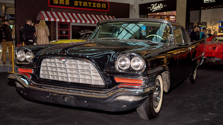A dark-colored Chrysler 300C from 1957 on display at a retro car show