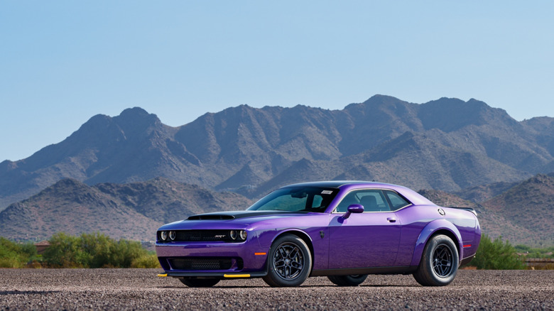 A left front-quarter image of a purple Dodge Challenger Demon 170 parked in an open area in front of a mountain range.