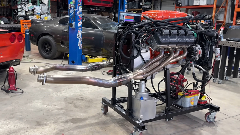 An orange and sliver custom-made Hellephant Hemi engine on a rack in a garage.