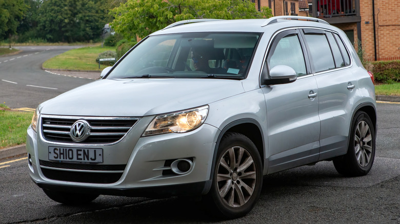 A silver VW Tiguan from 2010 parked just off a road in a suburban UK neighbourhood.