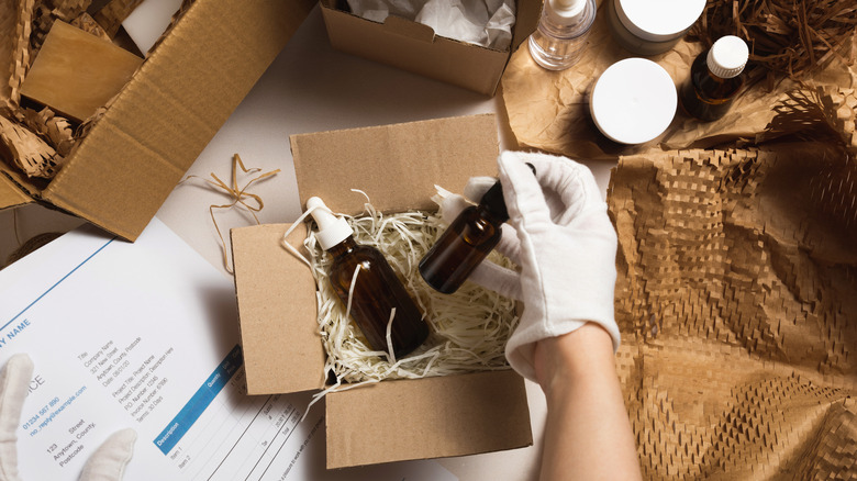 A person wearing gloves sorting through boxes of beauty products