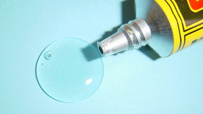 A tube of adhesive that is leaking onto blue paper