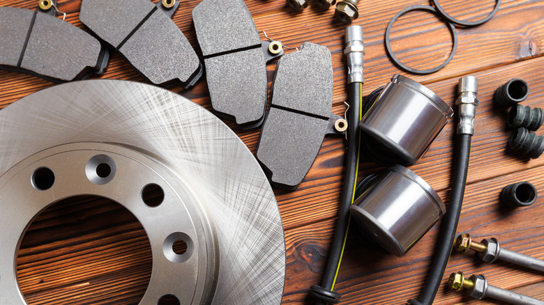 An assortment of new automotive brake components laid out on a wooden surface.
