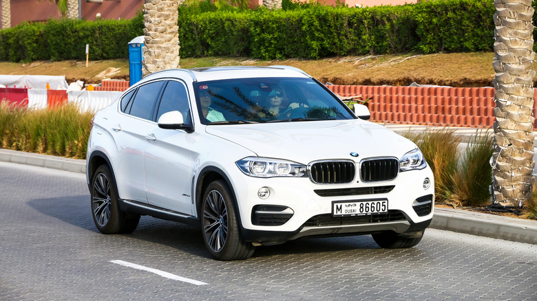 A  2018 BMW F16-chassis X6 moving along a city street on a cloudy day