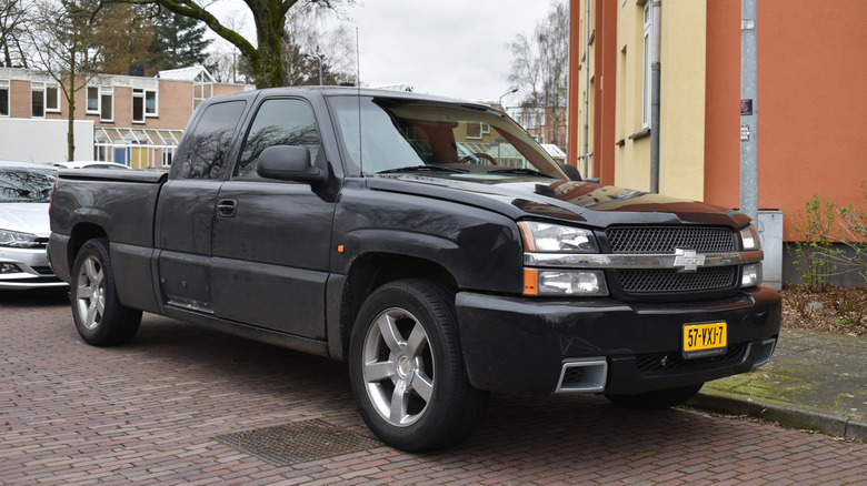 A black Chevrolet Silverado pickup truck parked on a brick street near a building.